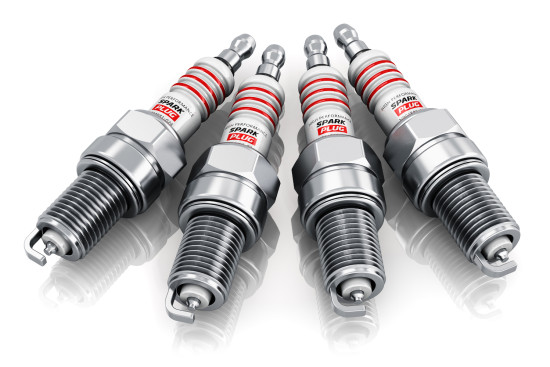 Creative car repair service and automotive transportation industry business concept: set of four metal spark plugs isolated on white background