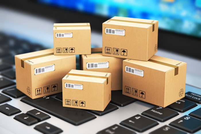 Macro view of heap of stacked corrugated cardboard package boxes on computer PC laptop notebook keyboard with selective focus effect